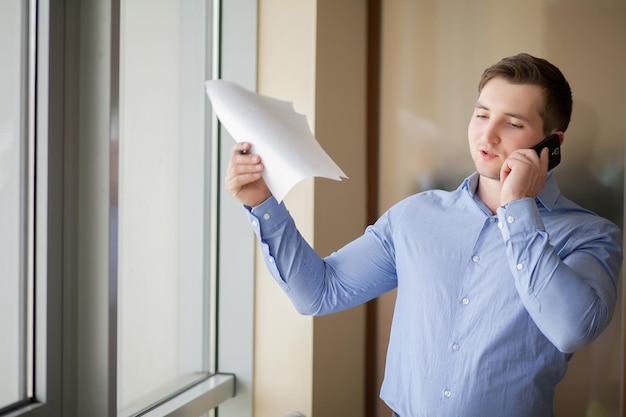 Homem de negócios bonito falando ao telefone no escritório