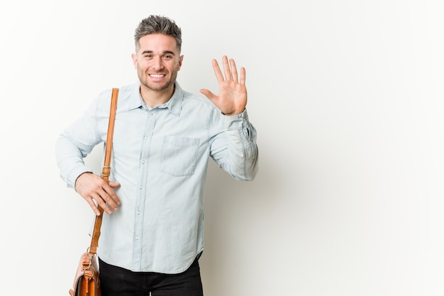 Homem de negócios bonito jovem sorrindo alegre mostrando o número cinco com os dedos.