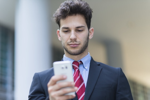 Homem de negócios bonito jovem usando seu celular