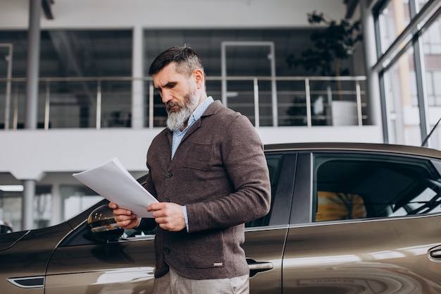 Foto homem de negócios bonito lendo documentos sobre aluguel de carros