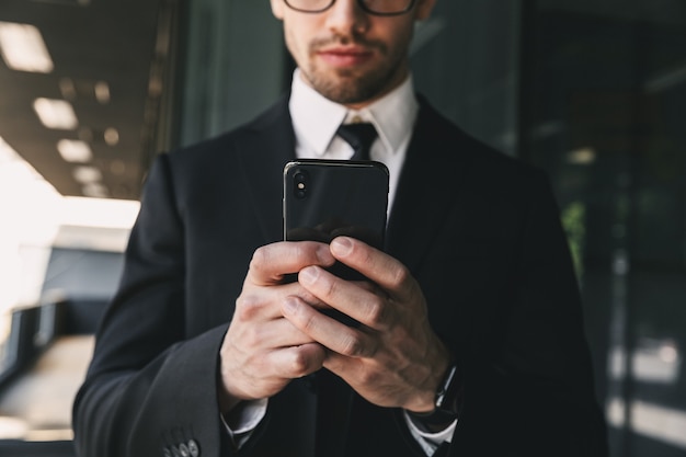 Homem de negócios bonito perto do centro de negócios, usando telefone celular.