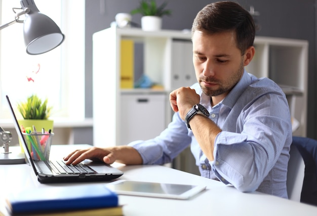 Homem de negócios bonito trabalhando com laptop no escritório