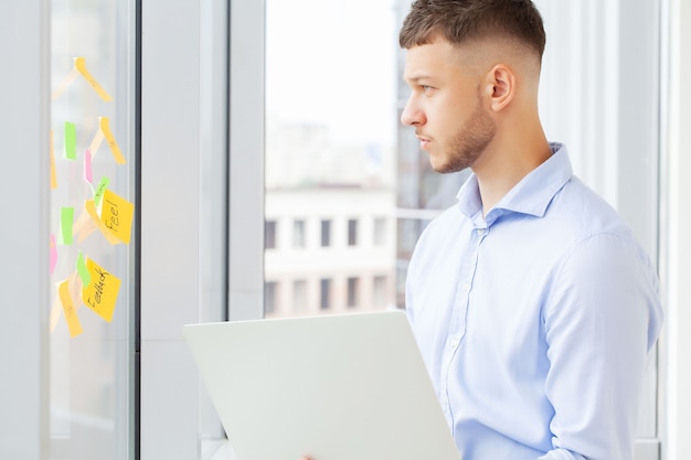 Homem de negócios bonito trabalhando com o laptop no escritório.