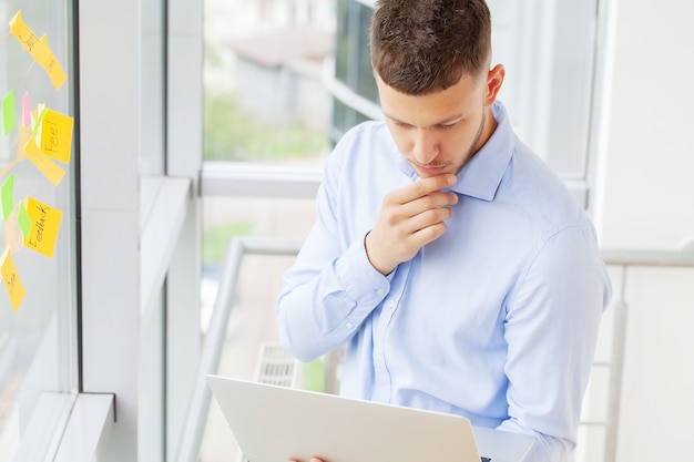 Homem de negócios bonito trabalhando com o laptop no escritório.