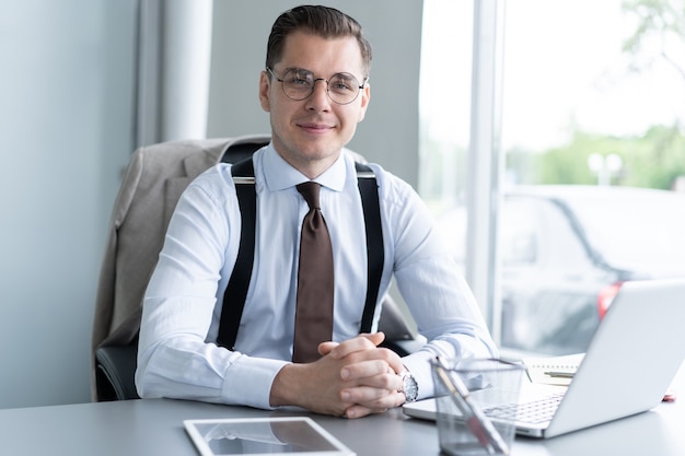 Homem de negócios bonito trabalhando com o laptop no escritório.