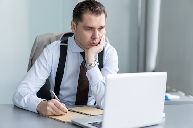 Homem de negócios bonito trabalhando com o laptop no escritório.