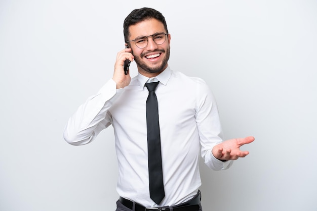 Homem de negócios brasileiro isolado em fundo branco, mantendo uma conversa com o celular com alguém