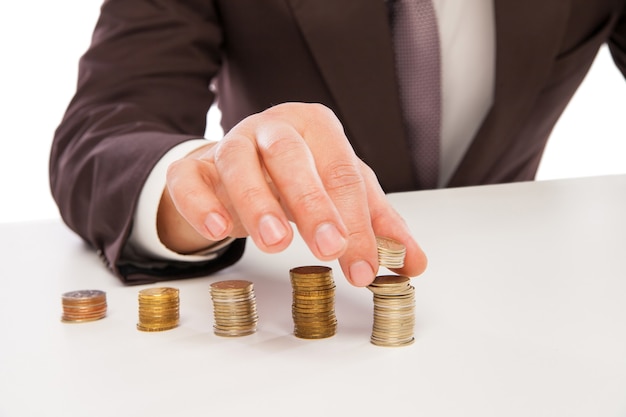 Homem de negócios calculando o lucro - close-up das mãos contando moedas isoladas sobre o branco