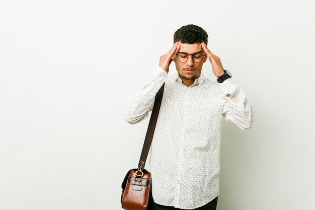 Homem de negócios casuais latino-americanos jovens tocando os templos e tendo dor de cabeça.