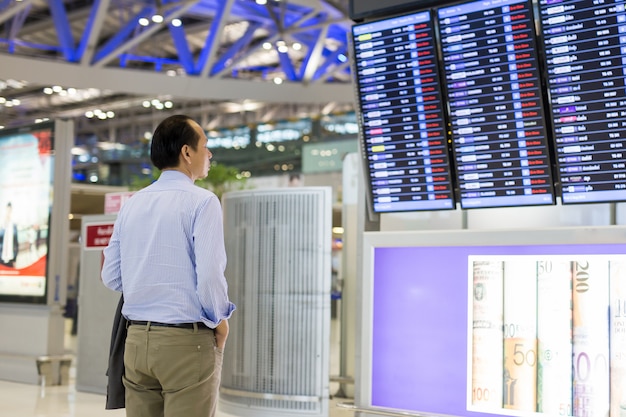 Homem de negócios com a trouxa no olhar do aeroporto no calendário do voo.