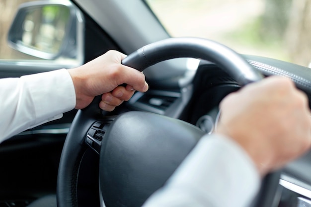 Homem de negócios com as mãos no volante de um carro luxuoso