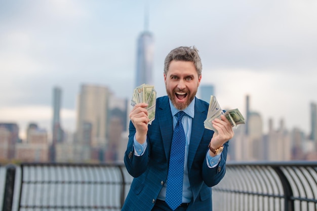 Foto homem de negócios com dólar ao ar livre homem de negócios entusiasmado com dinheiro de dólar na rua homem de negócios rico