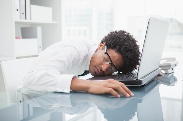 Homem de negócios com óculos dormindo no laptop