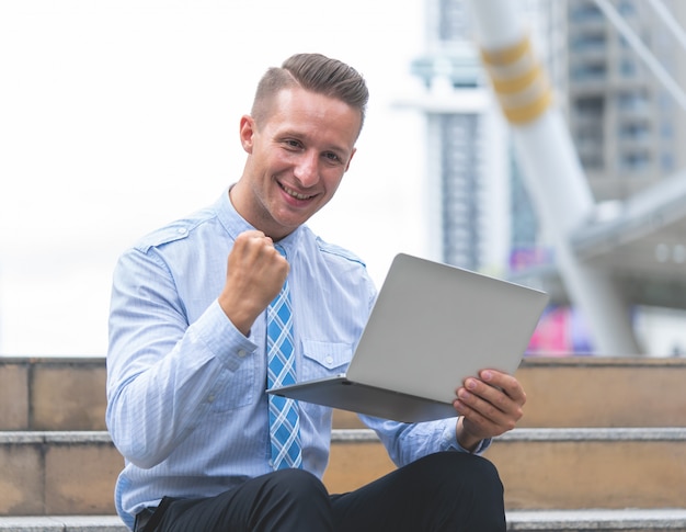 Homem de negócios com sucesso punho no laptop ao ar livre