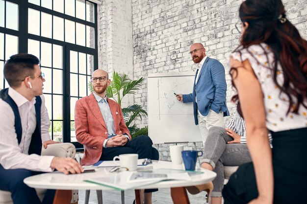 Homem de negócios confiante escrevendo em flipcharts apresentando novo projeto na reunião de empresa da diretoria