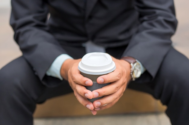 Homem de negócios considerável novo de Ásia que bebe o café quente na cidade moderna.