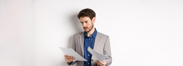 Homem de negócios de fato olhando através de papéis lendo documentos no trabalho ocupado em uma pessoa branca