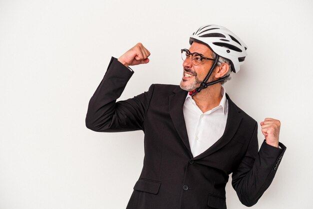 Homem de negócios de meia idade usando um capacete de bicicleta isolado em fundo azul, levantando o punho após um conceito de vencedor da vitória