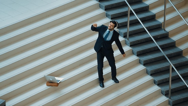 Foto homem de negócios de pé na escada enquanto se move para a música de fones de ouvido exultante