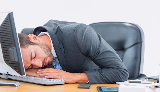 Homem de negócios descansando com cabeça sobre o teclado na mesa