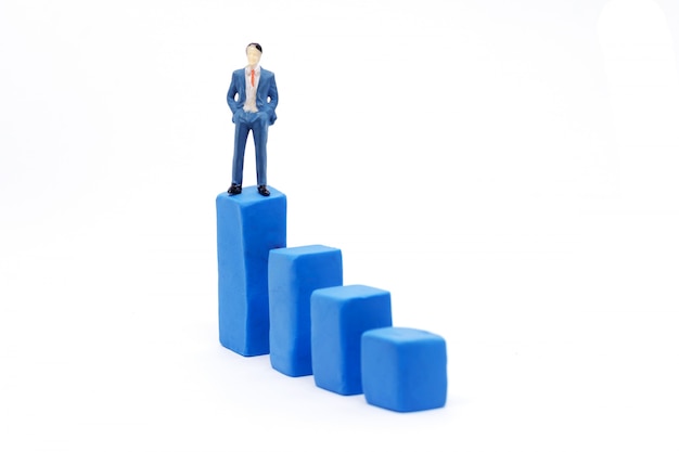 Homem de negócios diminuto e gráfico no fundo branco, conceito do crescimento do negócio