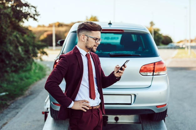 Homem de negócios elegante de meia-idade, chamando o serviço de reboque para obter ajuda na estrada. conceito de assistência na estrada.