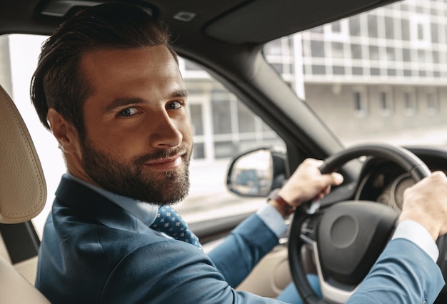 Homem de negócios elegante feliz no salão do automóvel