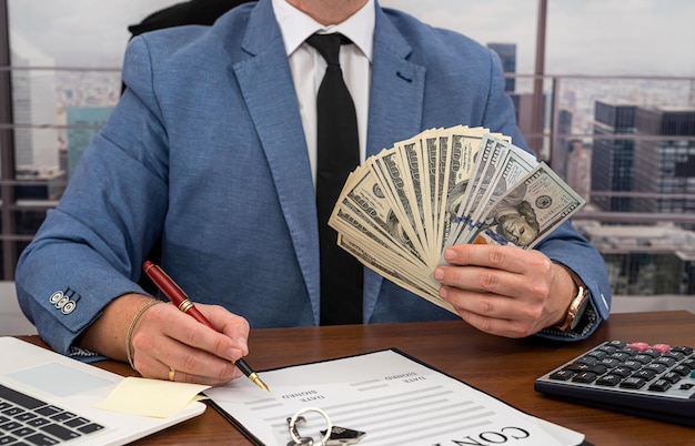 Homem de negócios em um terno estrito com dólares nas mãos assina um importante contrato de negócios Conceito de negócios e contrato
