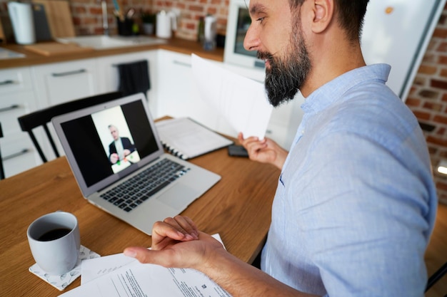 Foto homem de negócios em videoconferência através de laptop em casa