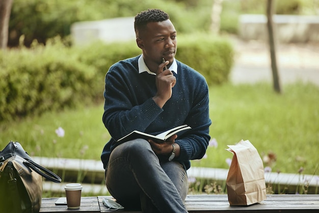 Homem de negócios escrevendo no livro de papel pensando em ideia criativa na cidade e almoçando no parque depois do trabalho Trabalhador empregado e pessoa corporativa trabalhando no cronograma e estratégia de planejamento com comida