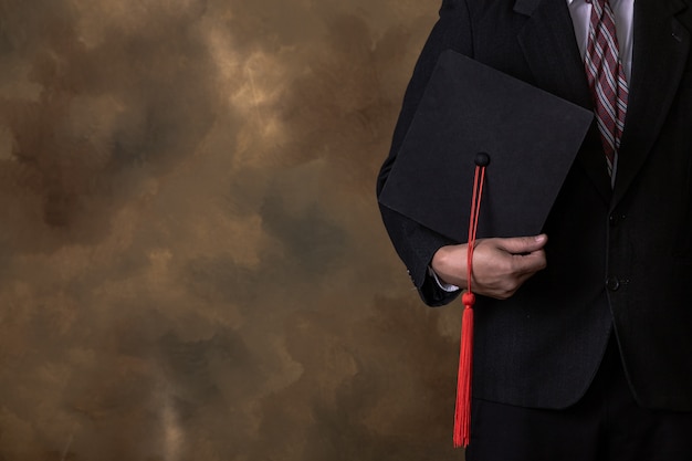 homem de negócios está segurando o chapéu de formatura