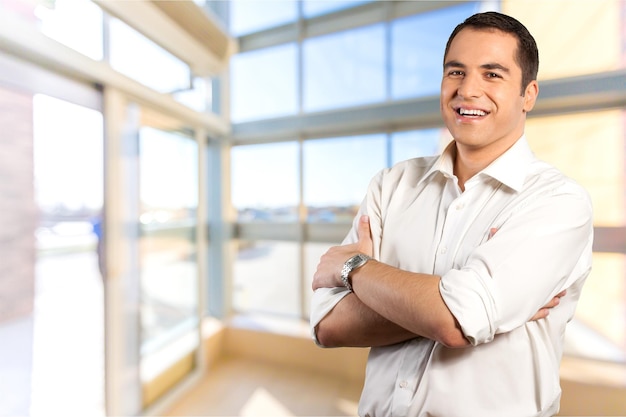 Homem de negócios feliz com as mãos cruzadas contra o branco