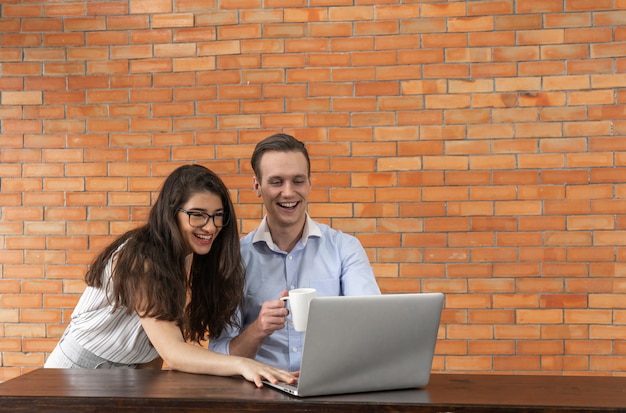 Homem de negócios feliz e mulher trabalhando juntos no laptop no café