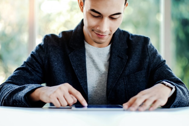 Homem de negócios feliz que trabalha na tabuleta de Digitas no escritório.