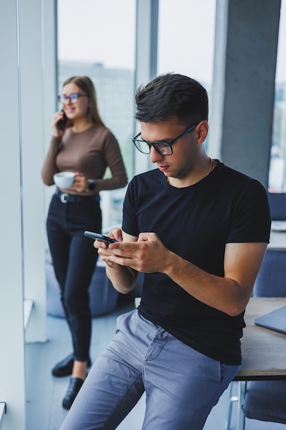 Homem de negócios feliz relaxado com um telefone nas mãos um estudante em sua mesa uma mesa em um café uma pessoa calma positiva relaxamento uma pausa um sonho um descanso do computador não sente estresse