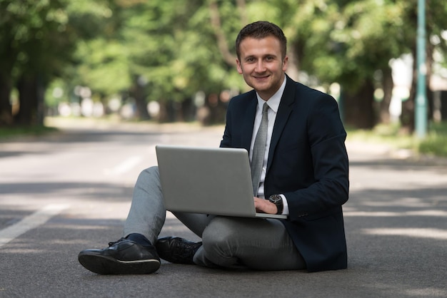 Homem de negócios feliz usando Tablet Pc fora no asfalto