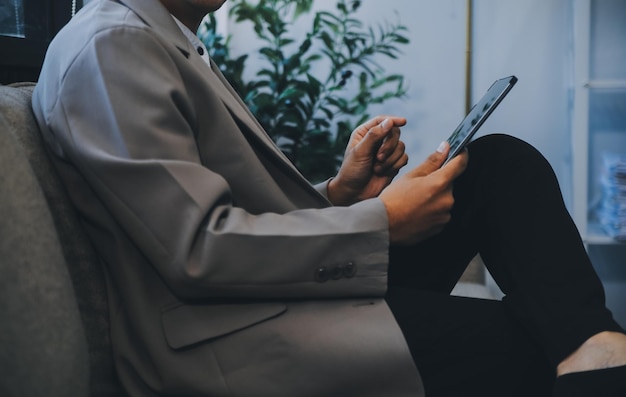 Homem de negócios feliz vestido de fato em um escritório moderno usando um tablet