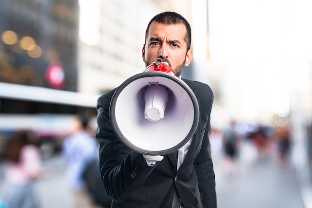 Homem de negócios gritando por megafone em fundo não focado