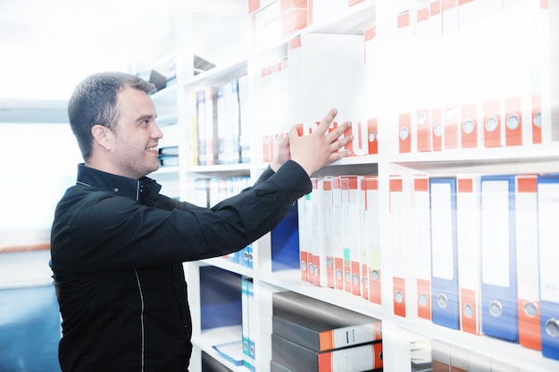 homem de negócios homem adulto em biblioteca de arquivo procurando e procurando livros e documentos que representam o conceito de armazenamento e educação