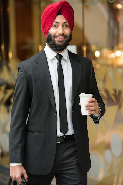 Homem de negócios indiano novo no turbante com café.