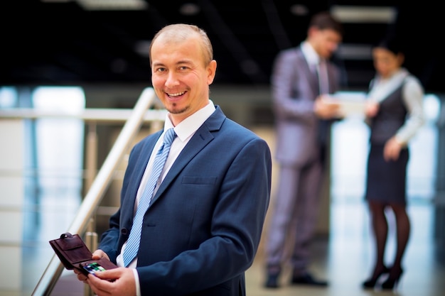 Homem de negócios inteligente e feliz com colegas de equipe discutindo em segundo plano