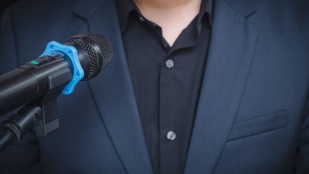 Homem de negócios inteligente falando e falando com microfones na sala de seminário ou na sala de conferências falando