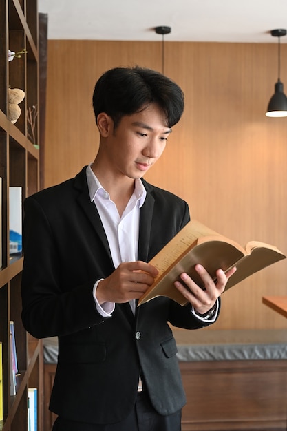 Homem de negócios inteligente lendo livro em um escritório moderno.