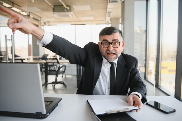 Homem de negócios irritado sentado à mesa e gritando