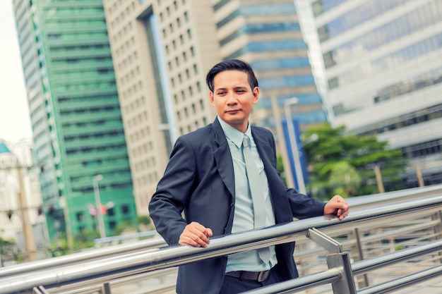 Homem de negócios jovem ásia na frente do edifício moderno no centro da cidade conceito de jovens empresários