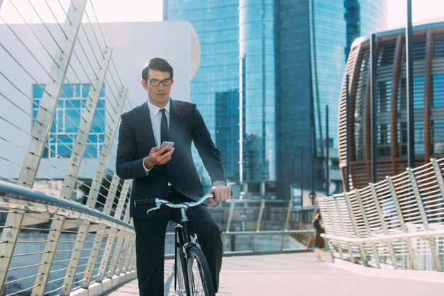 Homem de negócios jovem bonito com sua bicicleta moderna.