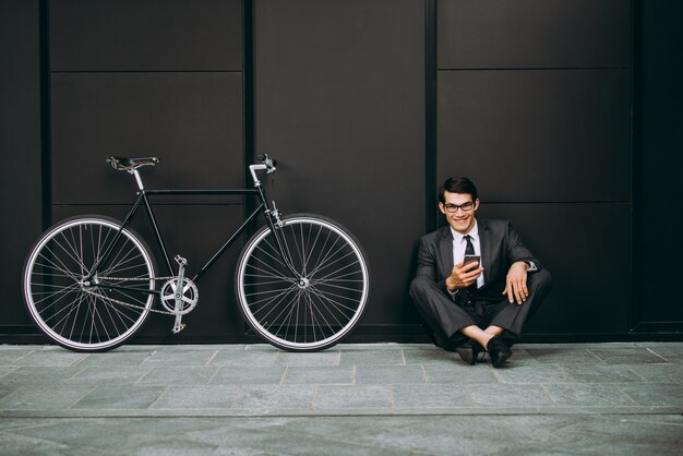 Homem de negócios jovem bonito com sua bicicleta moderna.