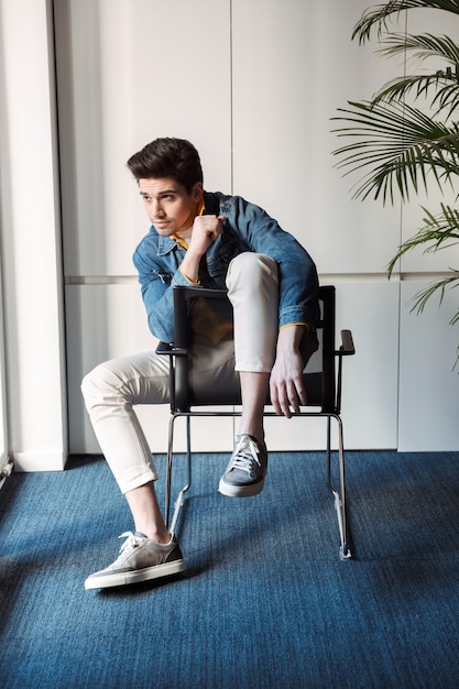 Foto homem de negócios jovem bonito sentado posando em um café dentro de casa.