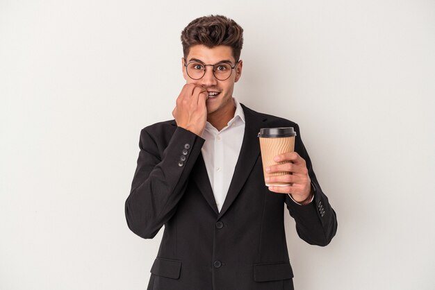 Homem de negócios jovem caucasiano segurando levar café isolado no fundo branco, roendo as unhas, nervoso e muito ansioso.