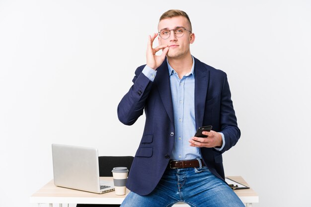 Homem de negócios jovem com um laptop com os dedos nos lábios, mantendo um segredo.